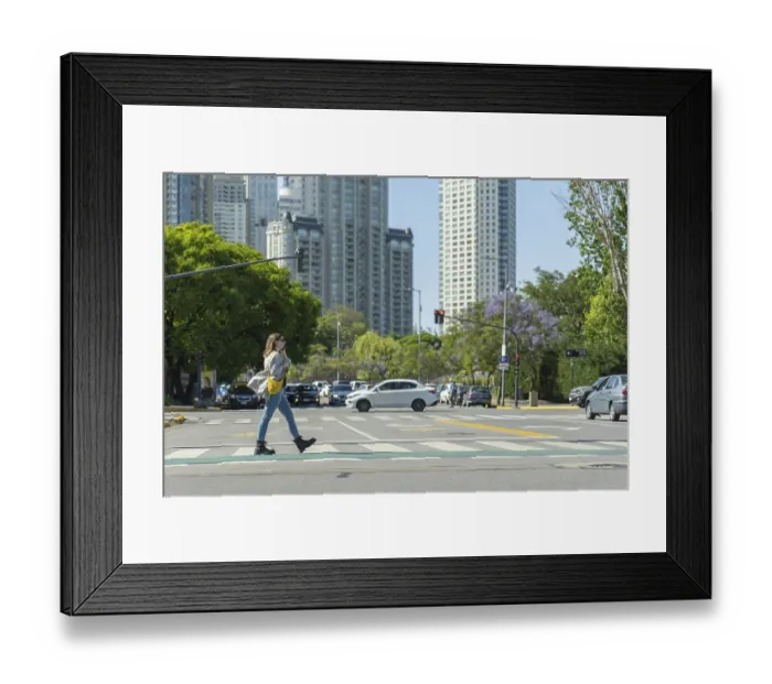 Framed Print : Young woman is crossing the street on pedestrian crossing in urban environment