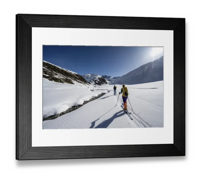 Framed Print : Two ski tourers in the snow by a mountain stream in the Funtauna Valley