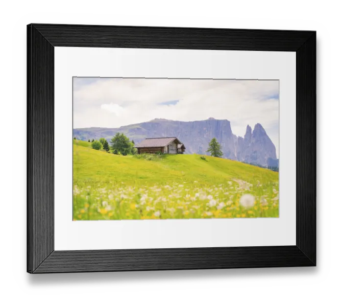 Framed Print : Alpine hut on a green meadow in front of a mountain range under a blue sky Framed Print : Alpine hut on a green meadow in front of a mountain range under a blue sky