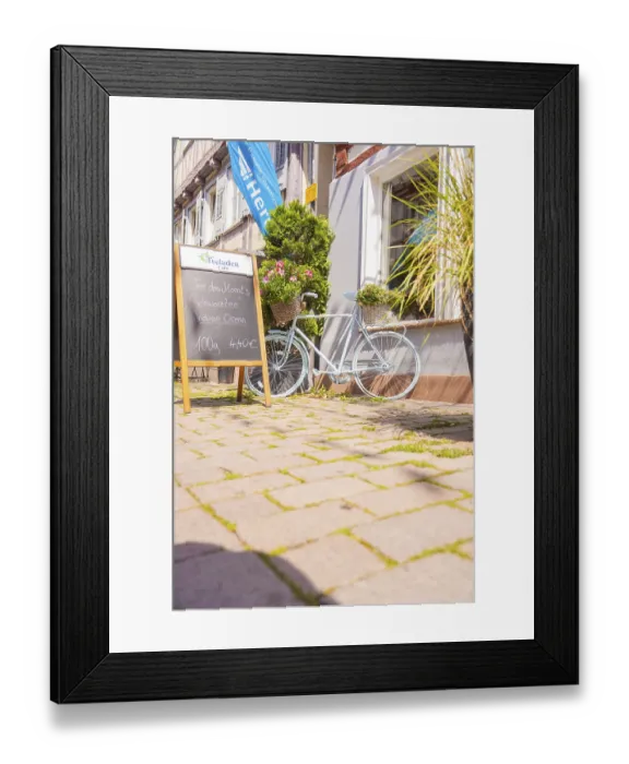 Framed Print : Bicycle with flower baskets and chalkboard in front of a cafe in the sunshine