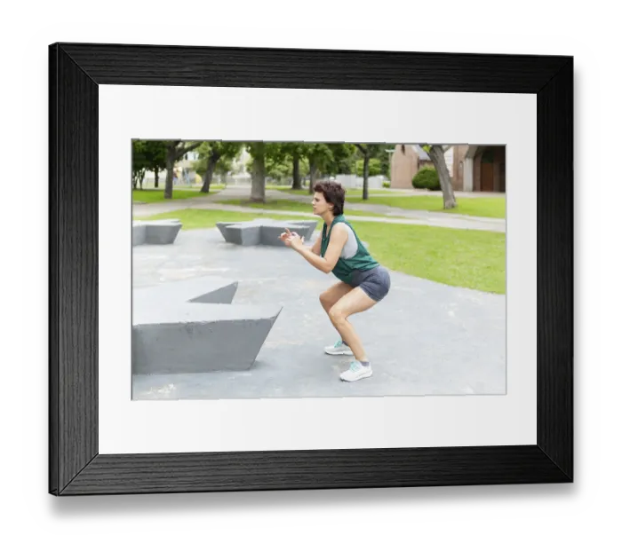 Framed Print : Woman performing a squat exercise in a park Framed Print : Woman performing a squat exercise in a park