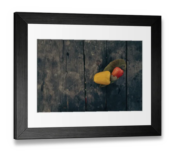 Framed Print : Red and yellow cashew fruits with a leaf on a textured aged wooden surface