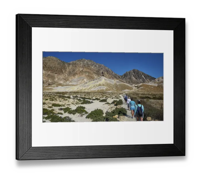 Framed Print : People walking on a path through a mountainous landscape under a clear sky