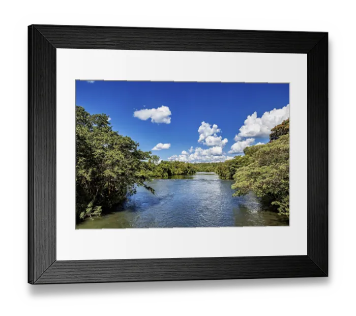 Framed Print : Lushly overgrown river course under a sky full of white clouds and blue