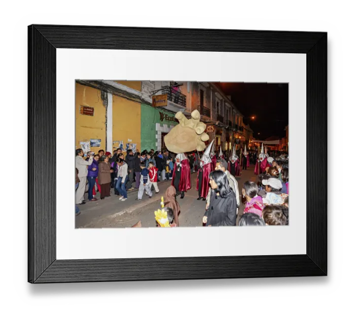 Framed Print : Participants in silver robes carry an oversized hand through the street at night