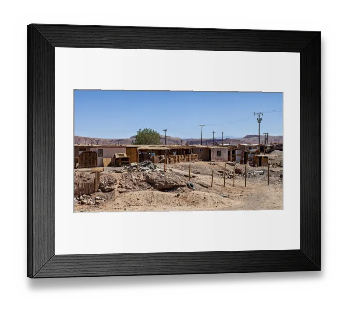 Framed Print : An arid landscape with simple buildings and electricity pylons under a clear sky
