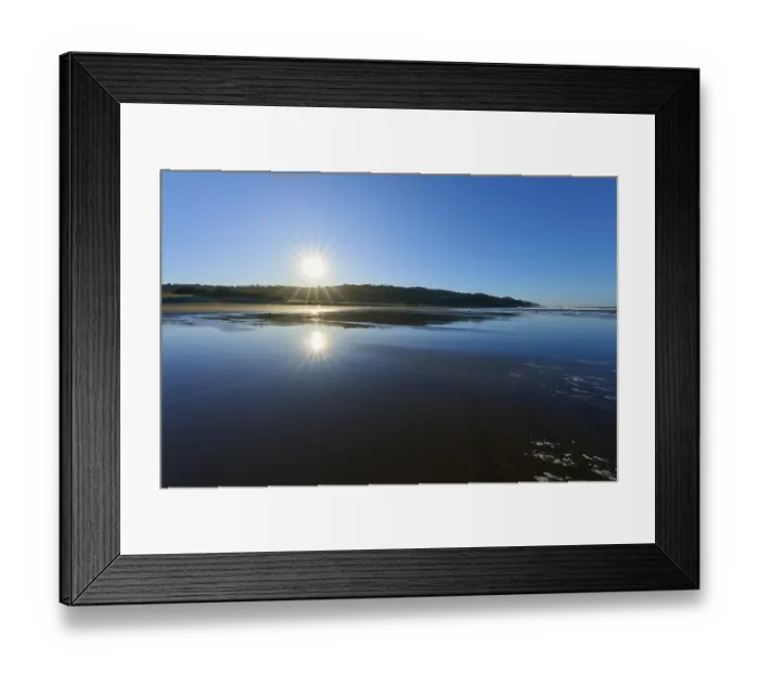 Framed Print : Early morning sun rays reflecting on the calm sea surface on a clear beach