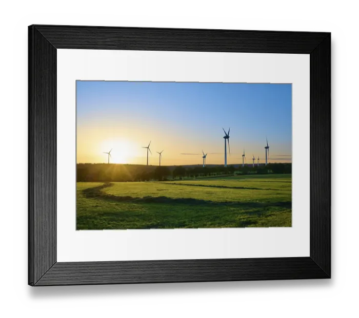 Framed Print : Wide landscape with wind turbines and trees while the sun colours the sky