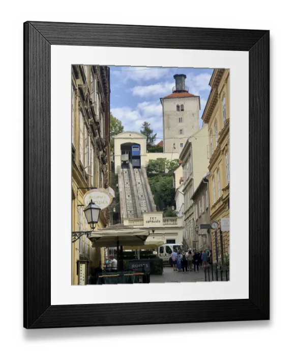Framed Print : Funicular railway runs in a narrow street surrounded by old buildings and a historic tower