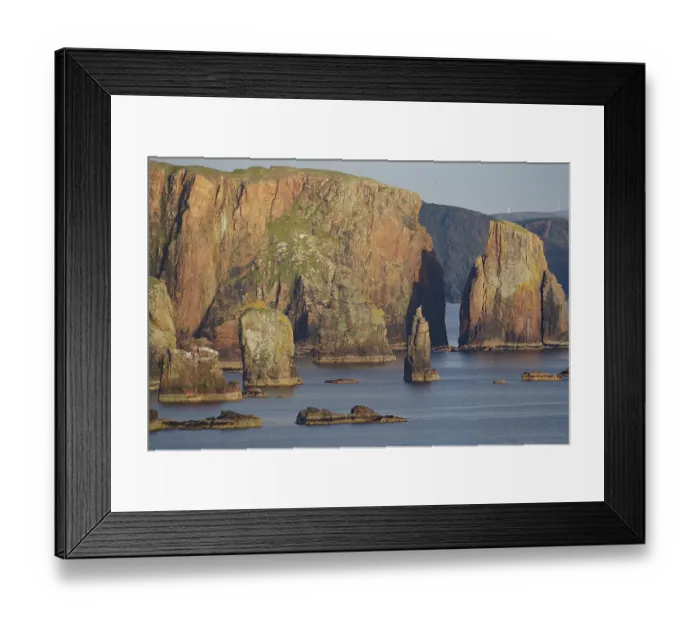 Framed Print : Towering cliffs and rocks in the sea under a clear sky