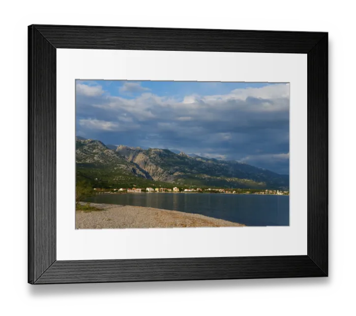 Framed Print : Coastline with mountains in the background under a cloudy sky Framed Print : Coastline with mountains in the background under a cloudy sky