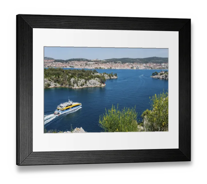 Framed Print : A boat sails through the clear blue water with a view of a town Framed Print : A boat sails through the clear blue water with a view of a town