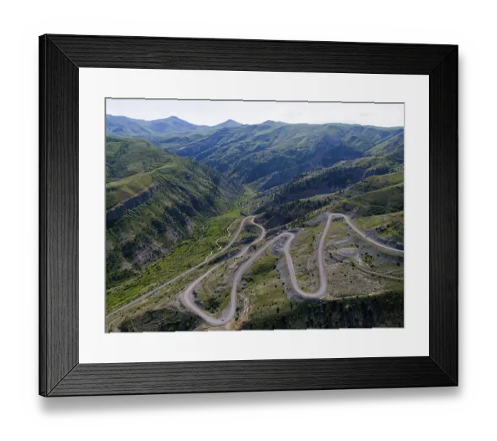 Framed Print : A winding serpentine road meanders through a green mountain landscape