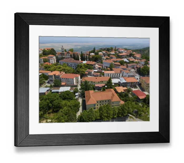 Framed Print : View of a hill town with traditional roofs and many trees in an extensive panorama