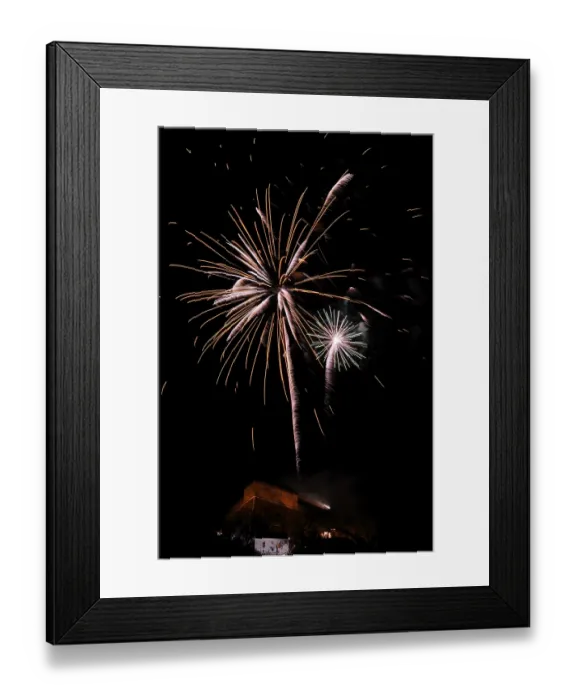 Framed Print : Fireworks light up the night sky above a building with glowing sparks