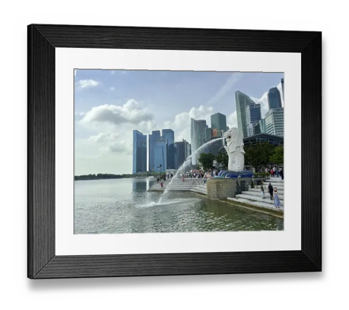 Framed Print : Merlion fountain spouts water in front of the impressive skyline and clouds