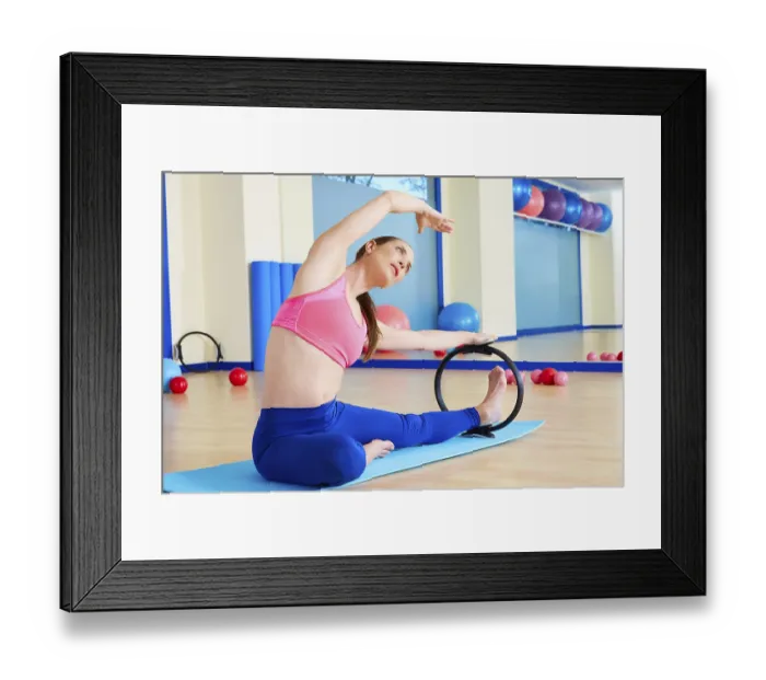 Framed Print : Pilates woman side stretch magic ring exercise workout at gym indoor