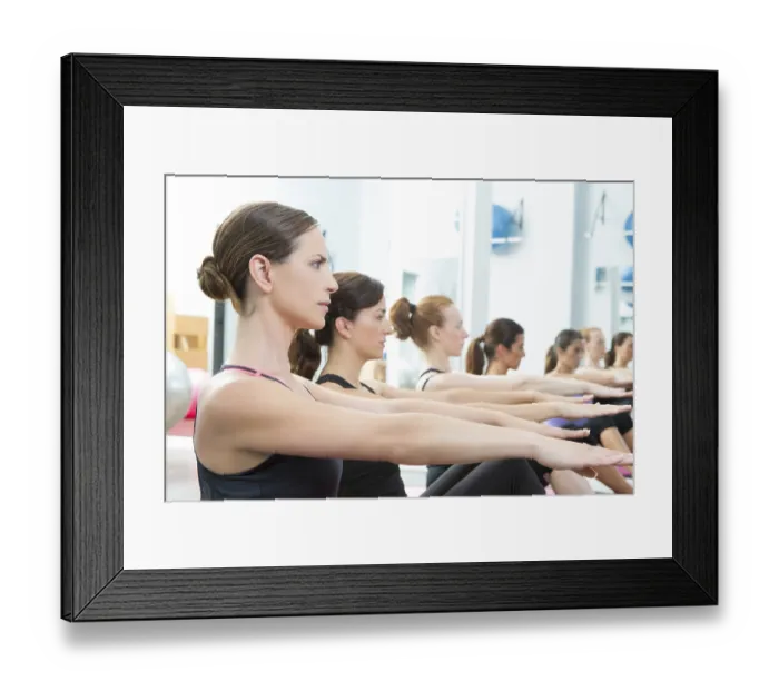 Framed Print : Aerobic Pilates personal trainer in a gym group class in a row