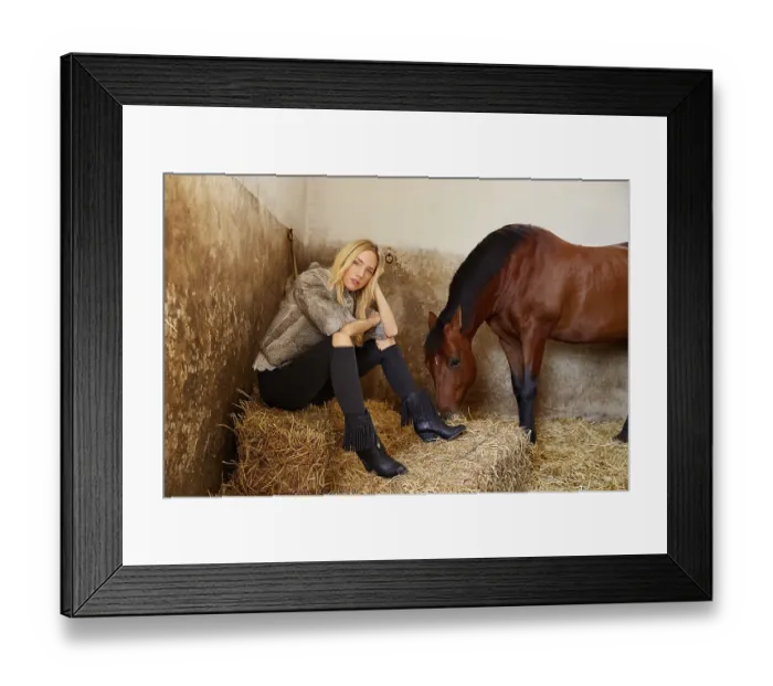 Framed Print : Blond woman on an indoor stable with a brown horse on straw bale