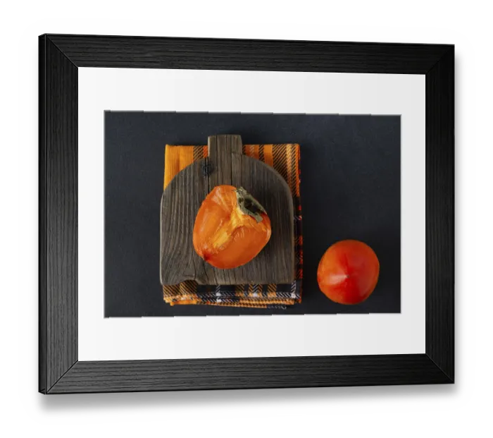 Framed Print : A piece of persimmon lies on a wooden board
