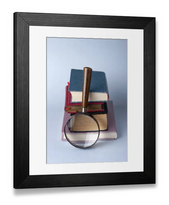 Framed Print : A stack of hardcover books and a magnifying glass on a blue background Framed Print : A stack of hardcover books and a magnifying glass on a blue background