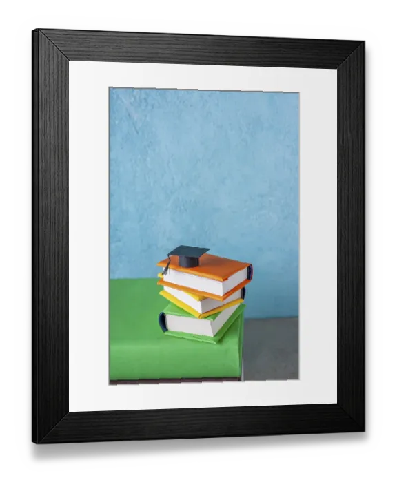 Framed Print : Student paper cap lies on a stack of books on a blue background Framed Print : Student paper cap lies on a stack of books on a blue background