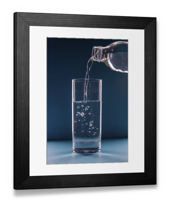 Framed Print : Water pours from a bottle into a glass on a blue background