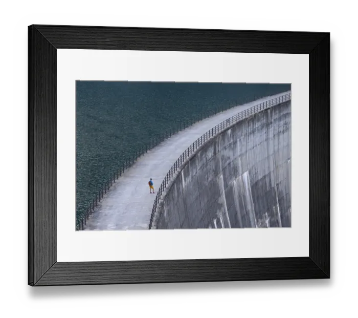 Framed Print : Woman, walking alone along a large dam with a view of the endless expanse of water Framed Print : Woman, walking alone along a large dam with a view of the endless expanse of water
