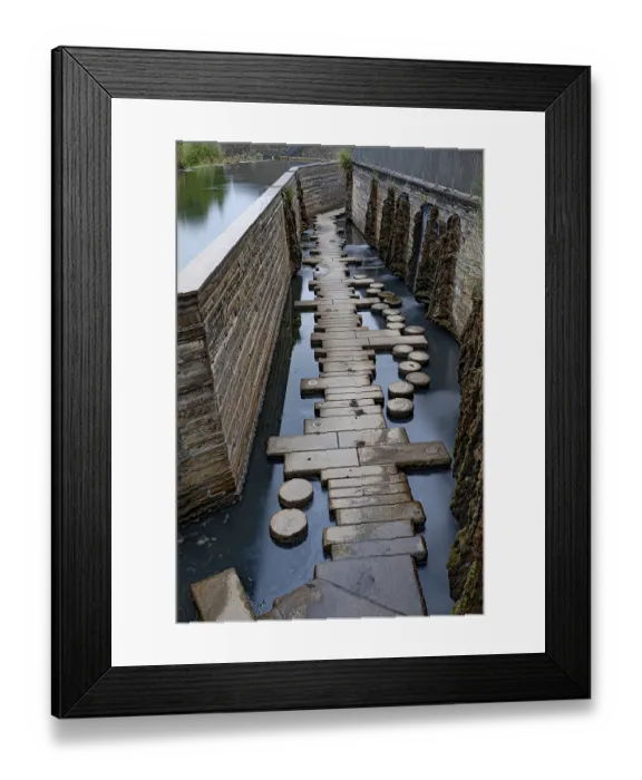 Framed Print : A path of stones leads through a narrow waterway next to a wall Framed Print : A path of stones leads through a narrow waterway next to a wall