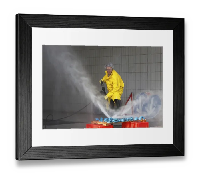 Framed Print : A worker in a yellow protective suit and goggles uses a high-pressure cleaner