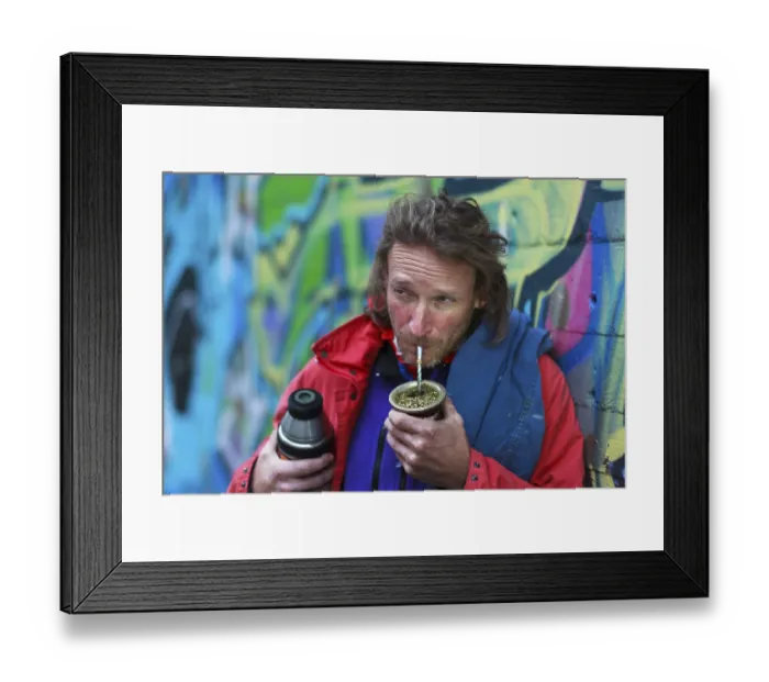 Framed Print : A man with a beard in colourful urban surroundings drinks mate from a cup