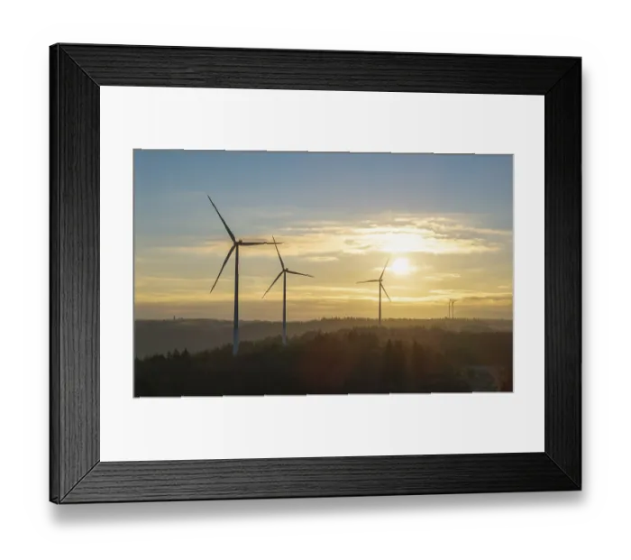 Framed Print : Three wind turbines under a clear sunrise sky over a forest landscape