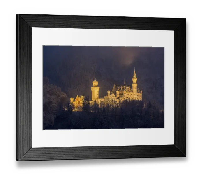 Framed Print : An enchantingly illuminated castle towers over a snow-covered mountain forest