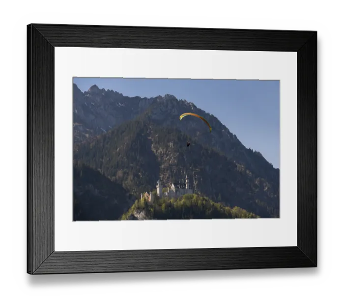 Framed Print : A paraglider flies over the majestic Neuschwanstein Castle in the picturesque mountains