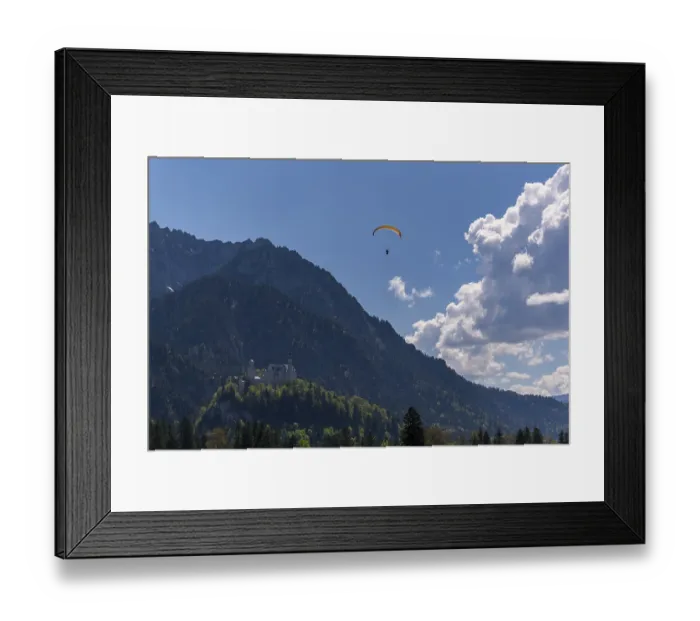 Framed Print : A paraglider over Neuschwanstein Castle with a cloudy sky