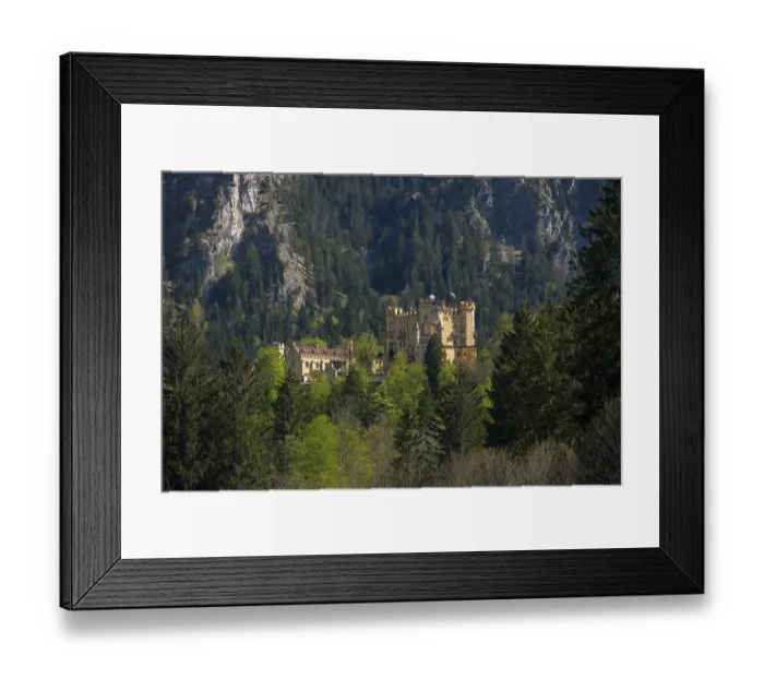 Framed Print : Hohenschwangau Castle is hidden in a dense mountain forest beneath dramatic towering cliffs Framed Print : Hohenschwangau Castle is hidden in a dense mountain forest beneath dramatic towering cliffs