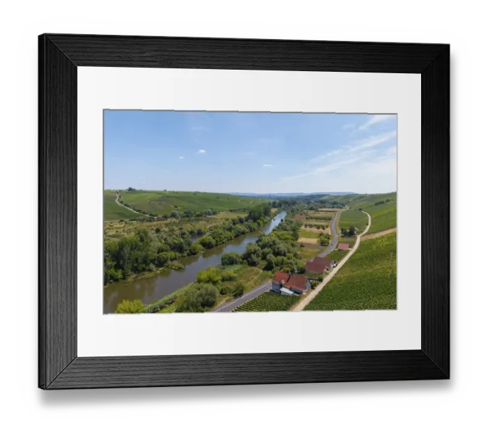 Framed Print : A river flowing through a landscape flanked by vineyards and a road