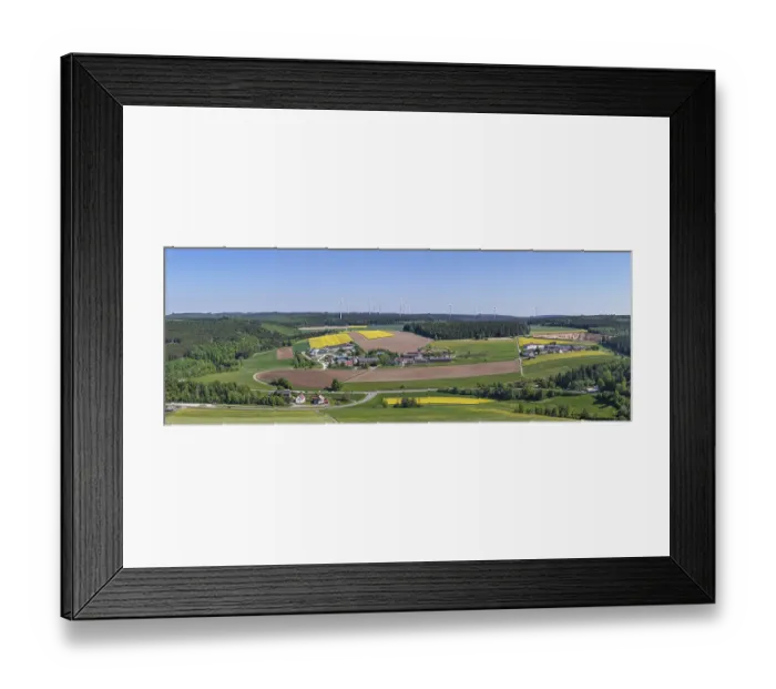 Framed Print : Far-reaching panoramic view of a village with surrounding fields and wind turbines