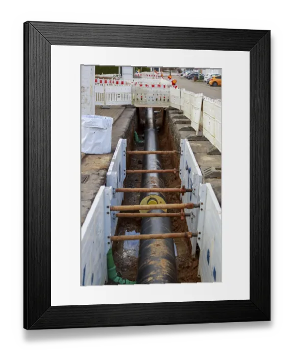 Framed Print : Large district heating pipeline runs through a construction site trench with stabilising wooden beams Framed Print : Large district heating pipeline runs through a construction site trench with stabilising wooden beams