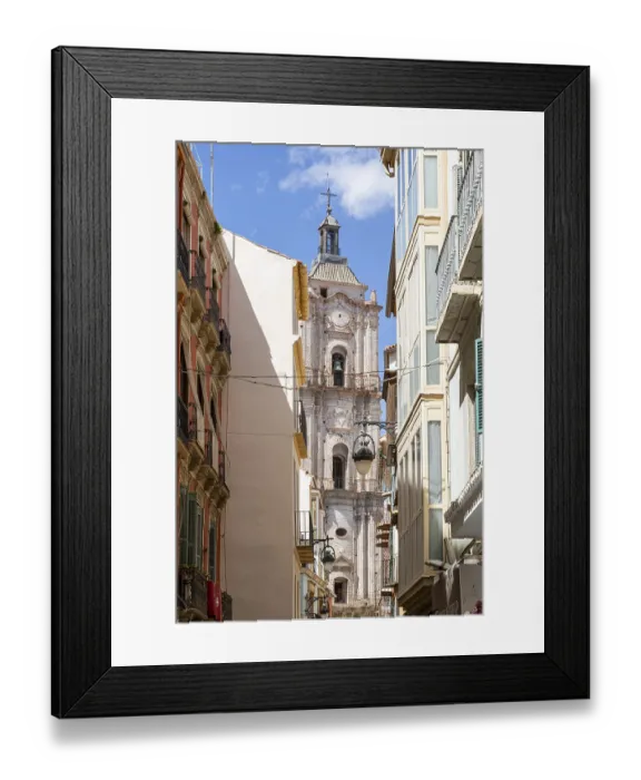 Framed Print : Narrow alley with a view of an old church tower under a clear sky