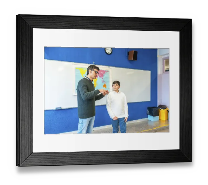 Framed Print : Geography teacher explaining lesson to elementary school student using a world map in a classroom Framed Print : Geography teacher explaining lesson to elementary school student using a world map in a classroom