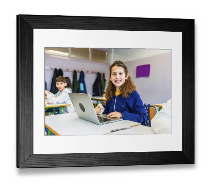 Framed Print : Elementary school student smiling and using laptop during class