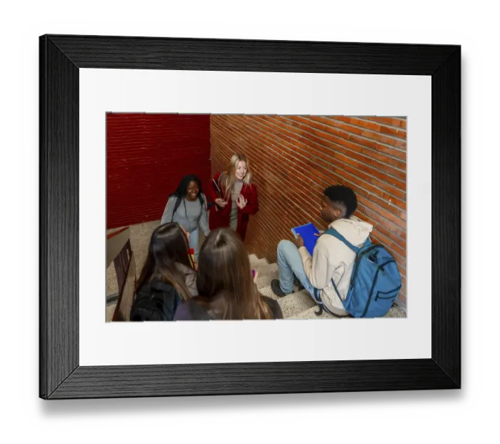 Framed Print : Multi ethnic students walking down the stairs and greeting a classmate sitting on the steps