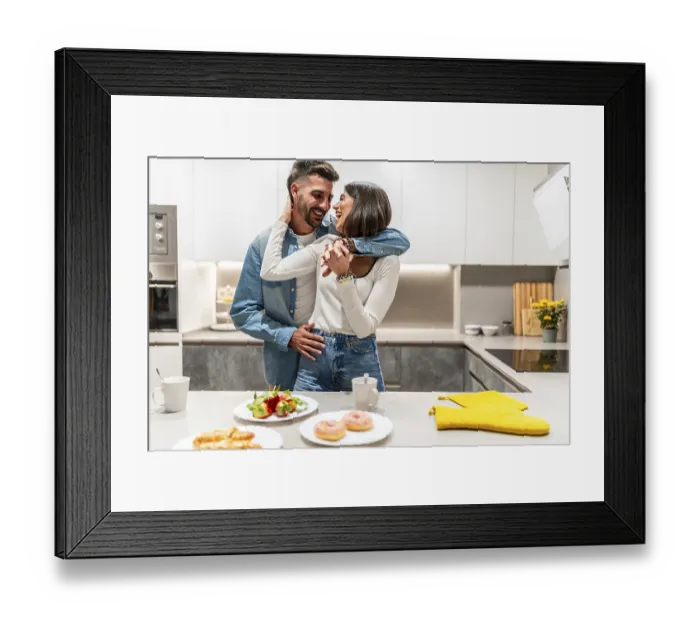 Framed Print : Young couple hugging and laughing in their modern kitchen