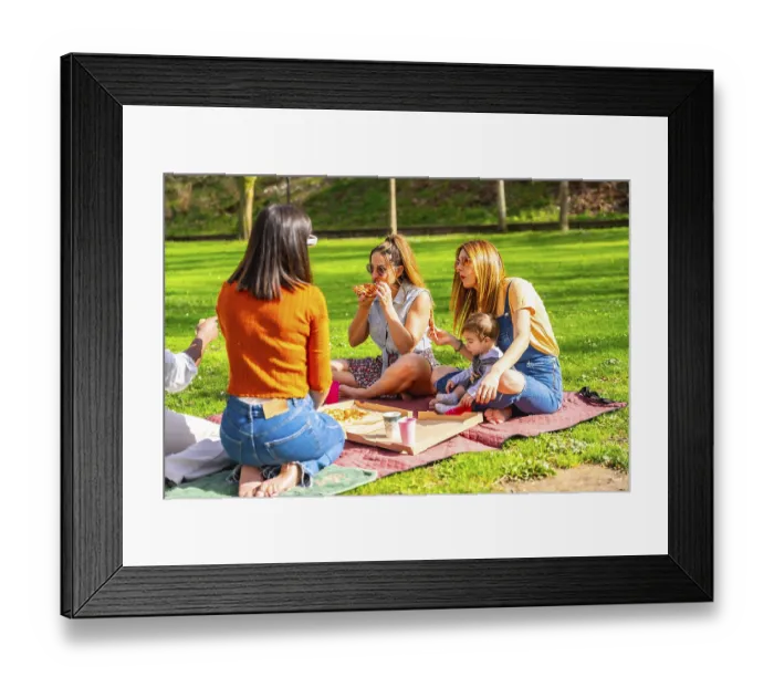Framed Print : Mothers, friends and children are sharing a pizza during a picnic in a park