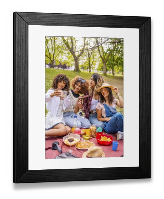 Framed Print : Four diverse female friends are enjoying a picnic in a park