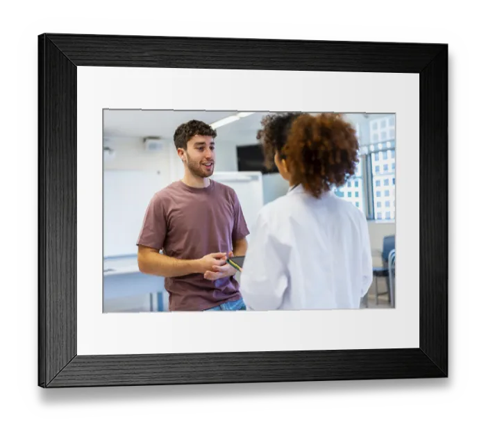 Framed Print : Young man holding a tablet, engaging in a conversation with a doctor inside a hospital room