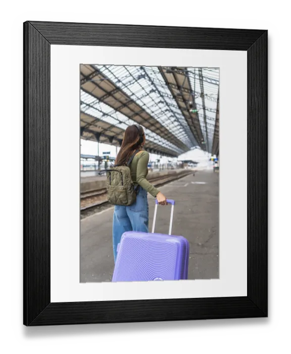 Framed Print : Tourist wearing headphones and carrying luggage strolls through a bustling train station Framed Print : Tourist wearing headphones and carrying luggage strolls through a bustling train station