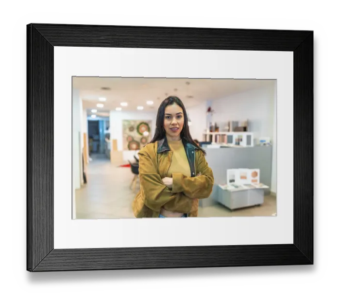 Framed Print : Portrait of a young saleswoman standing with arms crossed in a home improvement store