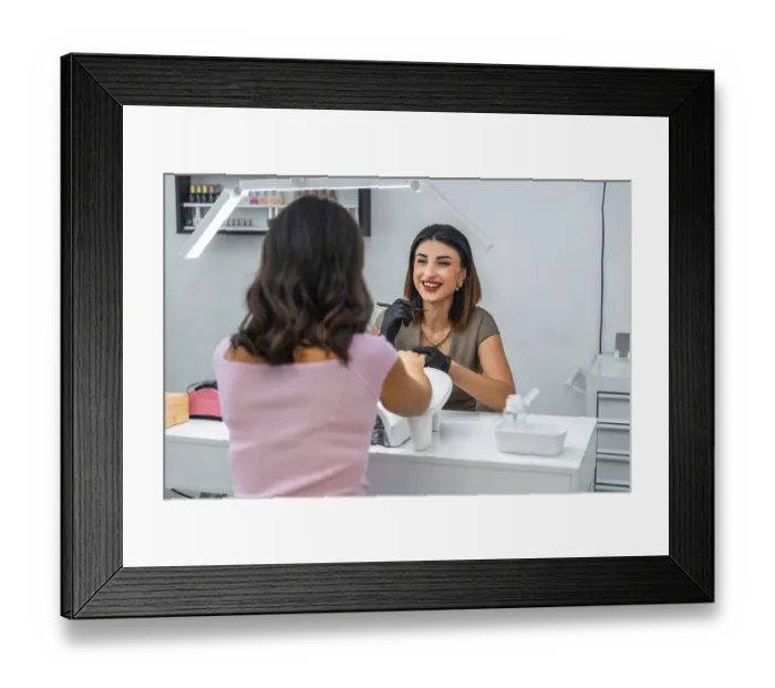 Framed Print : Smiling manicurist applying nail polish to her customer in a beauty salon